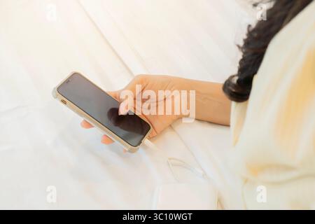 Unrecognizable woman lying on bed at home watching the mobile phone. Using smart phone concept. Stock Photo