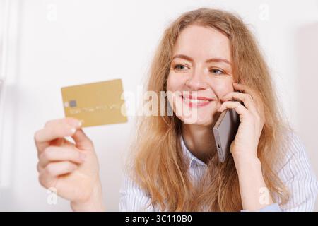 pretty smiling woman shopping online on phone but white background holding credit card talking on phone, smart payment, transaction, money, cash trans Stock Photo