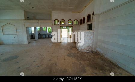 Abandoned interior with stone walls, arched windows, and tiled floor. Stock Photo