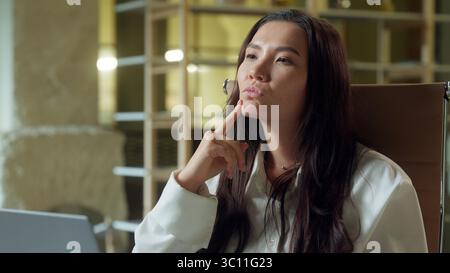 Asian businesswoman in office planning thinking laptop work Chinese business woman Korean Japanese girl female thoughtful worker employee happy Stock Photo