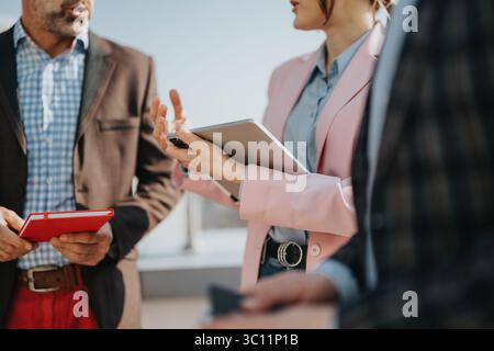 Team members having a discussion while reviewing notes and a tablet outdoors Stock Photo