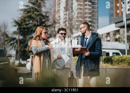 Three professionals collaborating outdoors in a modern urban environment Stock Photo