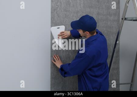 Worker smoothing wallpaper with tool in room Stock Photo