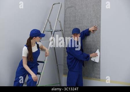 Worker smoothing wallpaper with tool in room Stock Photo