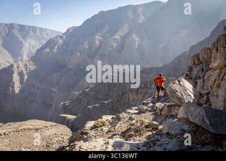 Male hiker with hiking poles and a backpack climbing on the Stairways to Heaven mountain trail from Wadi Ghalilah to Jebel Jais in Hajar mountains,UAE Stock Photo