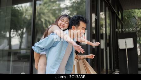 Joyful Family Enjoying a Holiday Shopping Adventure with Happy Parents and Excited Children in a Festive Urban Setting Stock Photo