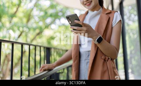 Confident Businesswoman Analyzing Stock Market Trends on Smartphone in Modern Office Setting Stock Photo