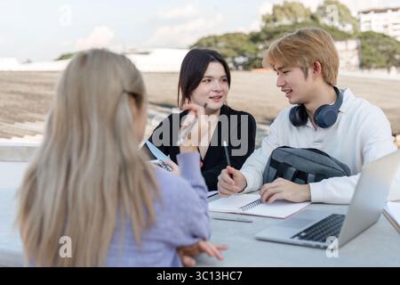 Young Students Collaborate Outdoors with Laptops and Notebooks for a Productive Study Session Stock Photo