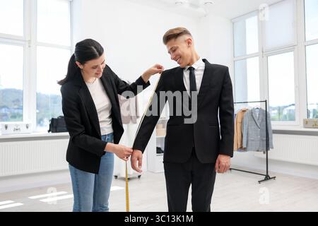 Tailor measuring jacket on man in atelier Stock Photo