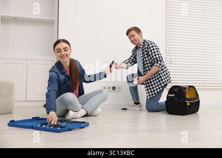 Couple with tools installing new socket at home Stock Photo