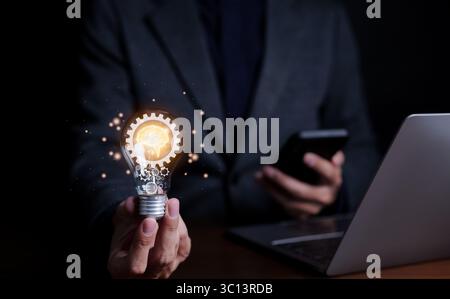 Motivation and innovation, Businessman holding light bulb with brain icon and gears inside. glowing light, idea innovation and inspiration, Stock Photo