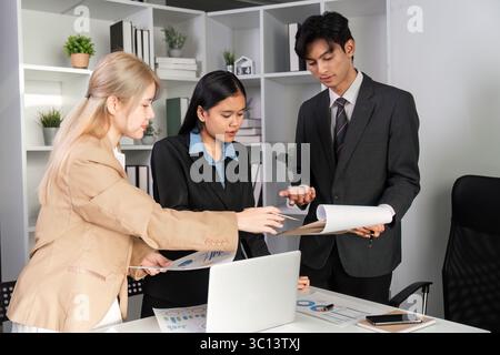 Business Team Collaborating on Data Analysis with Graphs in a Modern Office Setting Stock Photo