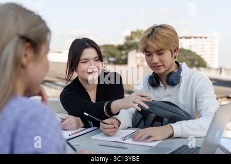 Diverse Group of Students Engaging in Online Learning Together Outdoors with Laptops and Notebooks Stock Photo