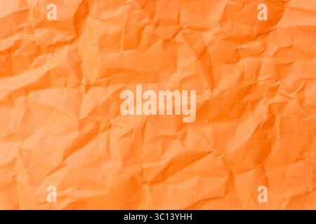 Top view and full frame of wrinkled or crumpled orange paper is used as crumpled orange paper background texture. Stock Photo