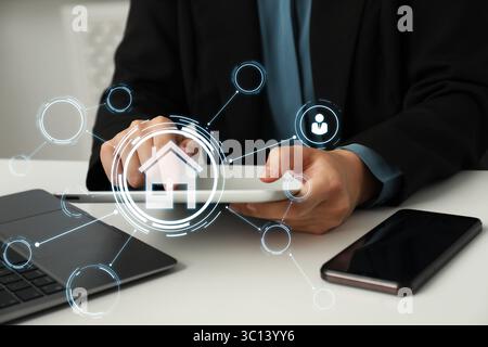 Real estate agent using table computer at table, closeup. Scheme with house icon on virtual screen Stock Photo