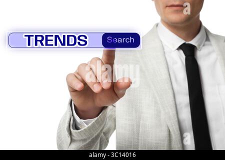 Businessman using virtual screen to find hot tendencies, new ideas, popular directions against white background, closeup. Search bar with word Trends Stock Photo