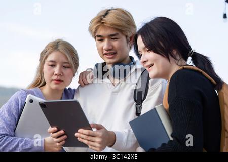 Diverse Group of Students Engaged in Online Learning Outdoors with Laptops and Tablets Stock Photo