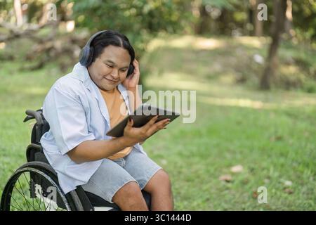 Young Disabled Businessman in Wheelchair Using Tablet for Outdoor Work in a Modern Green Environment Stock Photo