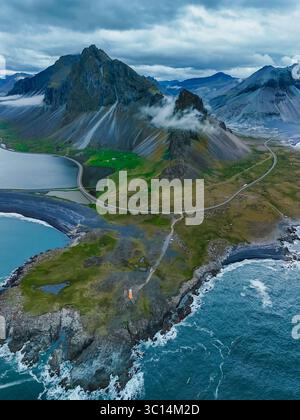 Aerial view of Vestrahorn mountain and the coastal road winding through ...