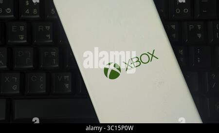 A white device showing the XBOX logo over a black keyboard Stock Photo