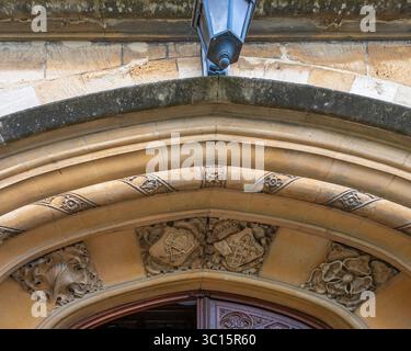 Moulded arched doorway, featuring heraldic shields at the entrance to St Catherine's church, High Street, Chipping Campden, Gloucestershire, England Stock Photo