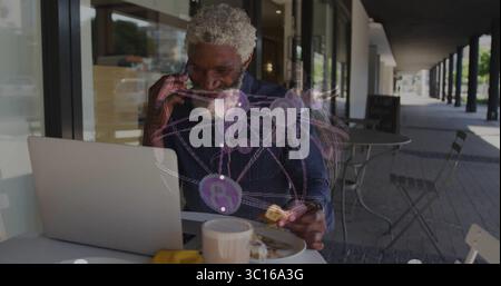Working man typing on laptop at café under overhang, with mug, sandwich, network hologram overlay Stock Photo