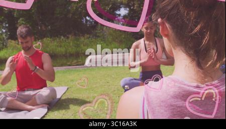 Practicing yoga trio wearing sportswear sitting cross-legged on sunny park lawn, with yoga mats Stock Photo