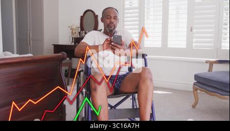Senior man sitting in wheelchair and using smartphone in bedroom, viewing colored line graphs Stock Photo