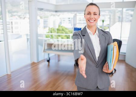Stack of colorful file folders resting on desk beside floor-to-ceiling windows in bright office Stock Photo