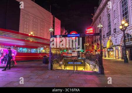 Piccadilly Circus underground entrance and speeding red Routemaster bus at night, London, England, UK. Night scene. Stock Photo
