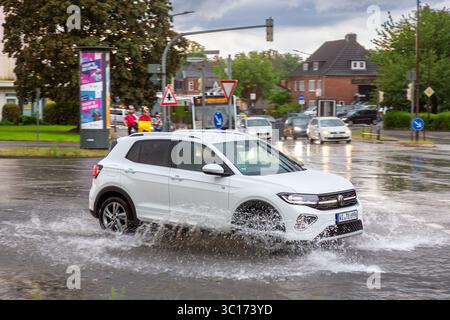 Car in torrential rain driving through flooded street in town after a heavy downpour / rainfall during thunderstorm in summer, Germany Stock Photo