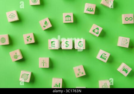 ESG Environmental Social Governance investment concept. Wooden cube with ESG word and Environment Icons on green background. Green business Stock Photo
