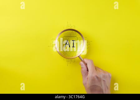 AI Artificial Intelligence technology concept. Man hand holding a magnifying glass focusing on an AI chip on yellow background. AI prompt generator, Stock Photo