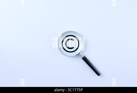 Copyright protection and patenting concept. Magnifying glass magnifies the copyright symbol on a white background. copyright symbol, Intellectual Stock Photo