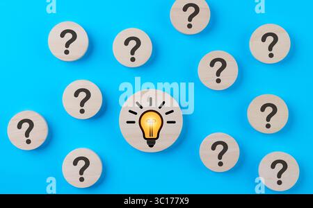 Problem solving concept. Question mark and light bulb icons on round wooden on blue background. Creative thinking, innovation, and idea, Business solu Stock Photo