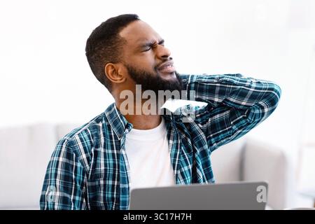 African Businessman Massaging Aching Neck Tired After Computer Work Indoor Stock Photo