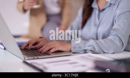 Professional hands inputting data on a laptop keyboard within a contemporary business setting. Focused work enhances productivity and digital collabor Stock Photo