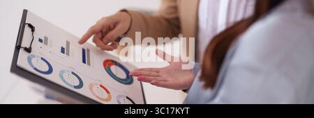 Two professionals analyze financial performance. They examine market trends discussing strategic insights. Business growth decisions are made with dat Stock Photo