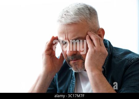 Closeup of mature grey-haired man suffering from migraine Stock Photo