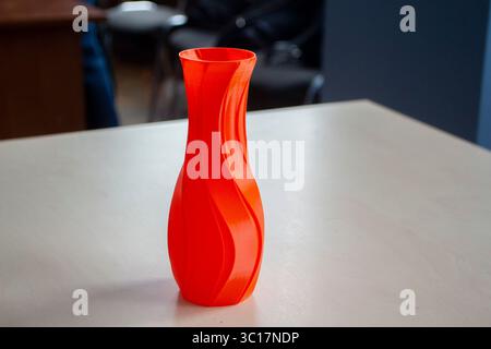 Object in form of vase of red color printed on 3D printer. Three-dimensional model printed on 3D printer from molten plastic of red color. FDM. 3D Printing technology. Concept 3D Printing. Stock Photo