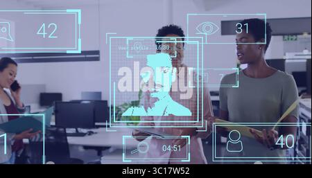 Collaborating women in blouses viewing facial recognition overlay in office, with smartphones Stock Photo