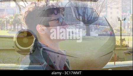 Showing man wearing sunglasses and coat merging private jet nose and turbofan engine at city park Stock Photo