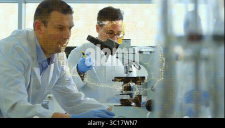 Scientists in lab coats examining slide under microscope at lab bench, with pipette data overlay Stock Photo
