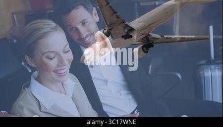 Executives in suits using tablet leaning in airport lounge, with suitcase, airplane, copy space Stock Photo