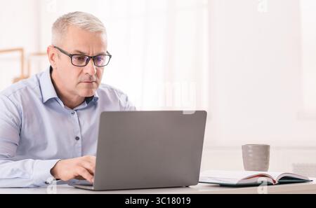 Serious senior man using laptop at office Stock Photo