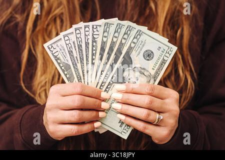 Woman holding stack of US dollar bills. Fan of twenty dollar banknotes. Close up hands with manicured nails. Financial success and savings. Stock Photo