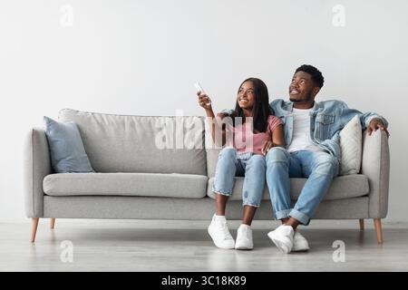 Young black woman switching on air conditioning at her home Stock Photo