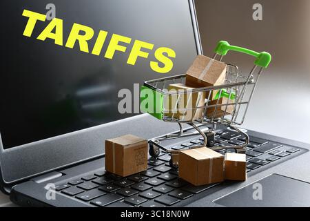 A shopping cart with packages and packaging on a laptop keyboard and the word "Tariffs" on the screen. A concept for new customs tariffs. Stock Photo