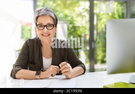 Cheerful mature woman business consultant working at office Stock Photo