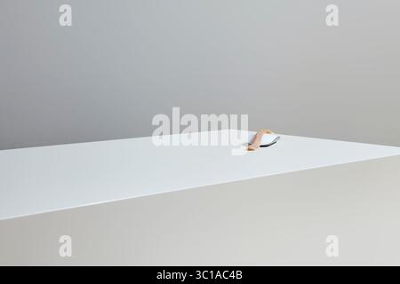 A computer mouse rests on a white, rectangular surface. Covered with a slice of raw fish. The background is a plain, light gray wall. The lighting is Stock Photo